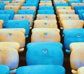 Colorful rows of empty stadium seats create a vibrant pattern with alternating blue and yellow hues.
