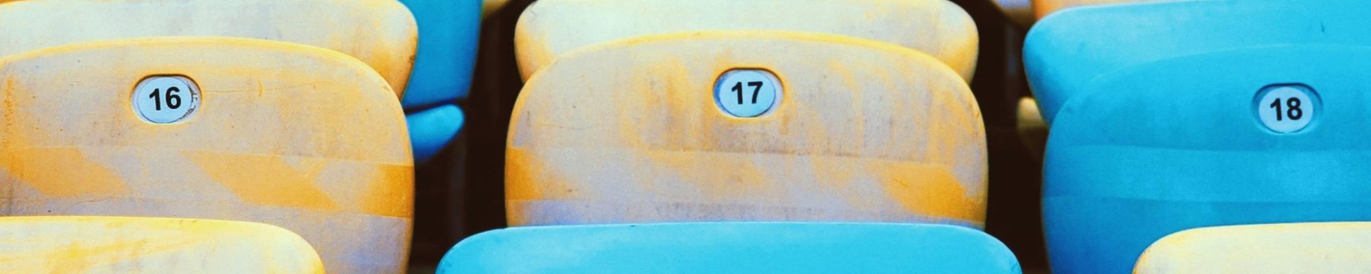 Colorful rows of empty stadium seats create a vibrant pattern with alternating blue and yellow hues.
